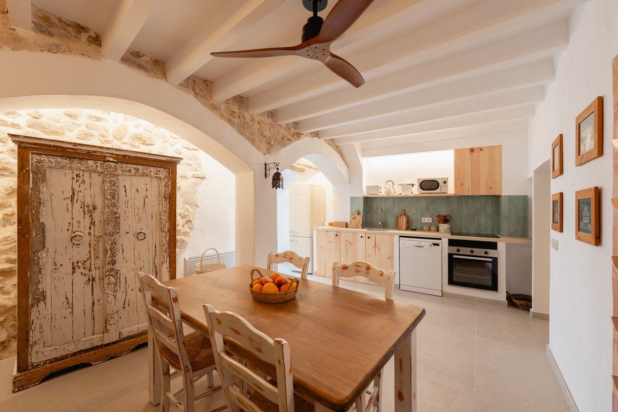 The light-wood kitchen, with the dining table and terracotta wine rack.