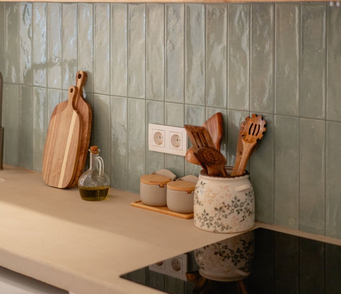 Kitchen detail: handmade green tiles, wooden boards, oil and wooden spoons.