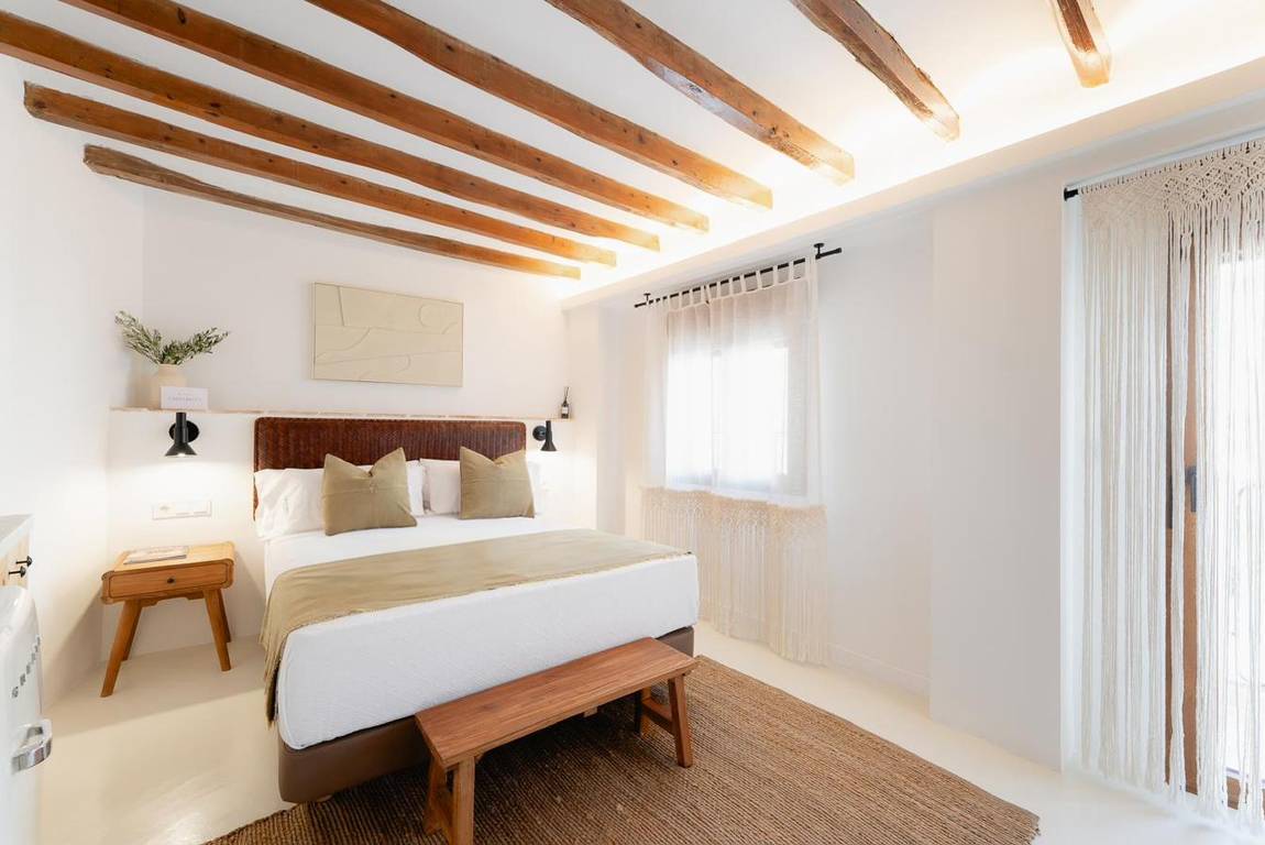 Arbequina: woven leather headboard and dark beams.