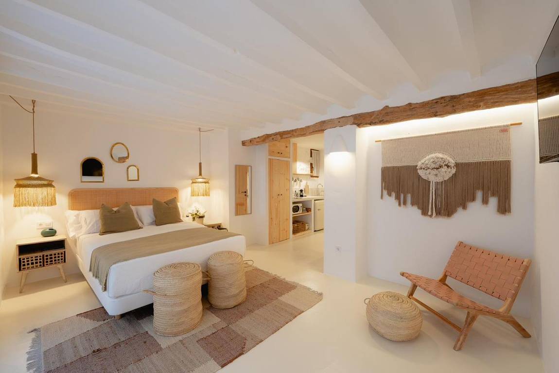 Blanqueta: bed with a rattan headboard and macramé hanging.