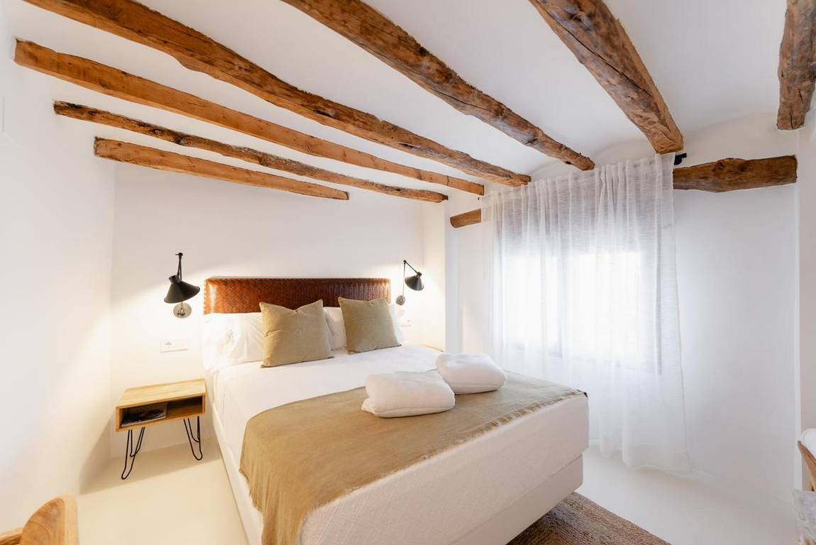 Manzanilla, second bedroom: leather headboard and a desk beneath the beam.