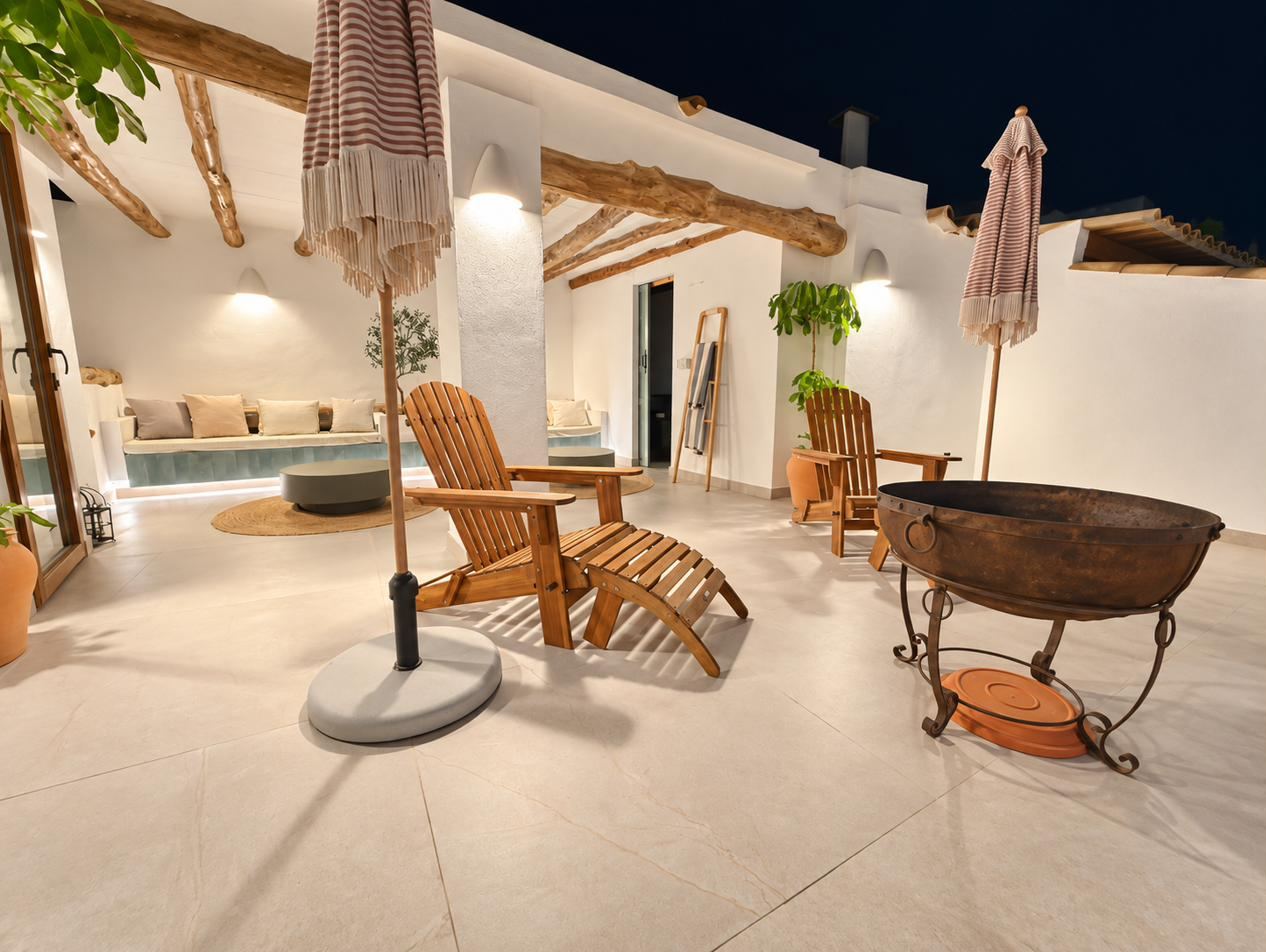 The roof terrace at night: long bench beneath the pergola, wooden chairs and the fire bowl.