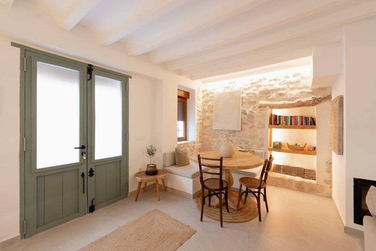 The entrance: green double door, built-in bench and a round table by the stone.